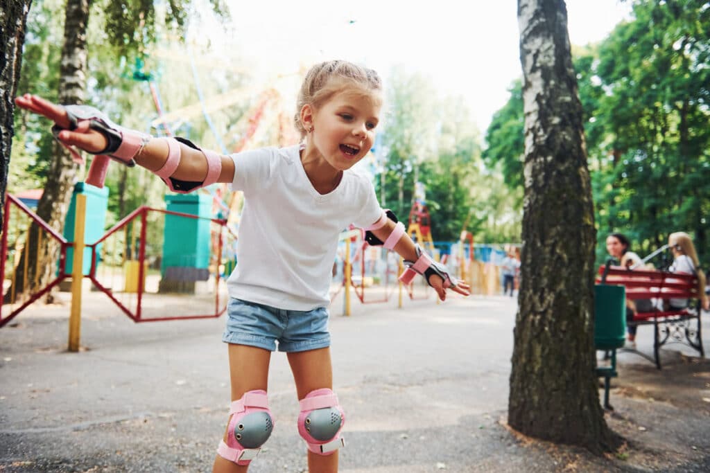 flicka med fläta och armarna ut som åker inlines i en lekpark