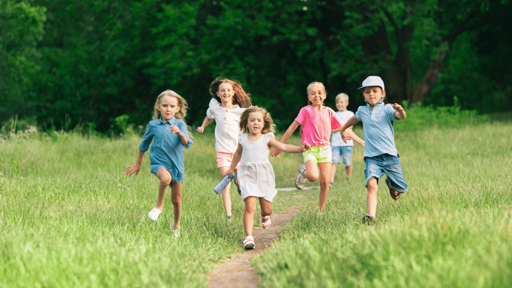 Barn som springer på en gräsäng iklädda sommarkläder